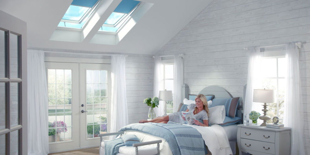 A bedroom with two skylights with shades.