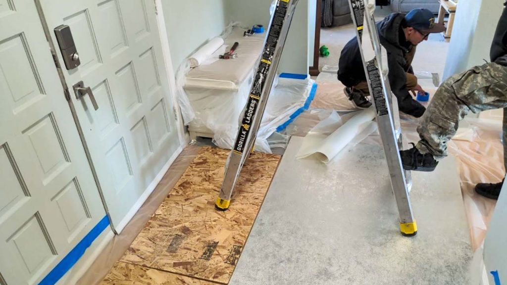 Protecting the home with plywood on the floor and plastic sheeting over furniure.