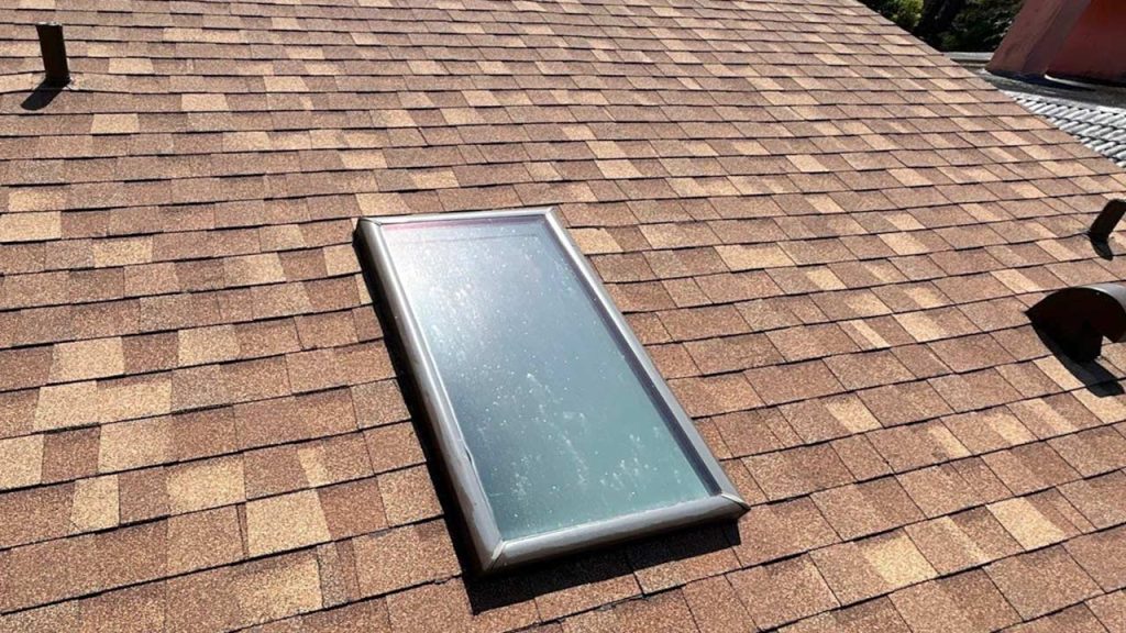 A roof featuring a glass skylight, allowing natural light to illuminate the interior space below.