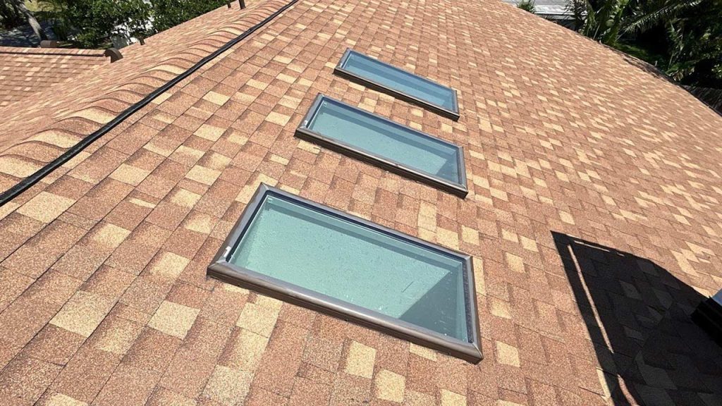 A roof showcasing three glass skylighst, providing a view of the sky and increasing daylight indoors.