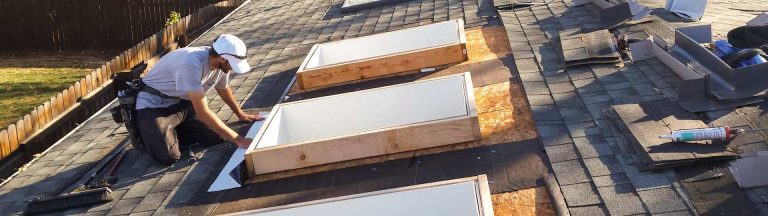 A technician on the roof installing nderlayment around a skylight curb..