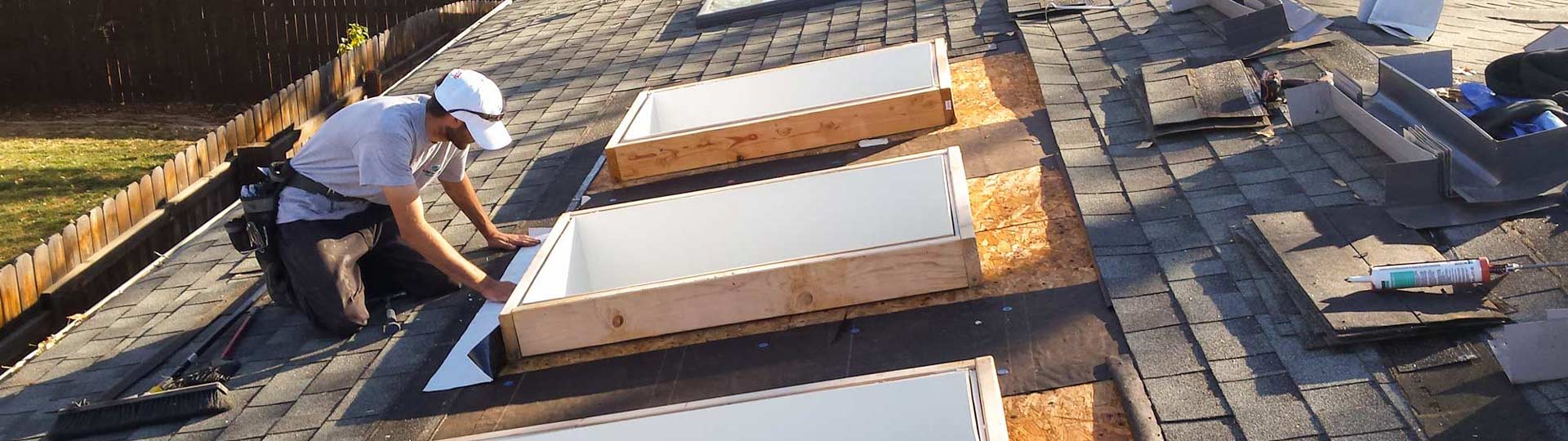A technician on the roof installing nderlayment around a skylight curb..