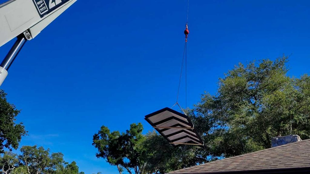 American Skylights ridge-mount skylight being hoisted onto a residential roof by crane in Florida.