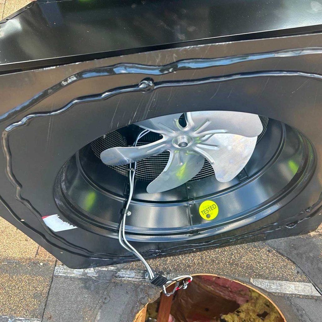 Pre-installation inspection of the Attic Breeze SFA-4523A solar attic fan unit, showing the underside blade assembly and flashing base.